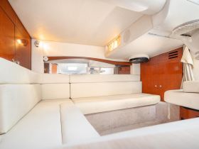 Interior view of a cozy boat cabin featuring plush seating and elegant wood finishes, perfect for relaxing during a day on the water.