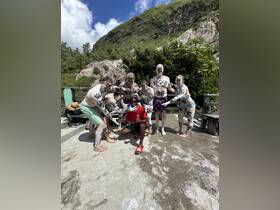 A lively group enjoys a fun mud bath experience, showcasing their painted bodies against a stunning natural backdrop — perfect for adventurous outings.
