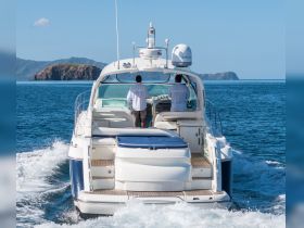 Two crew members navigate a sleek boat through clear blue waters, showcasing the beauty of ocean adventures and the thrill of being underway.