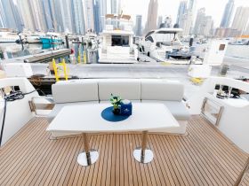 A stylish interior view of a boat's lounge area featuring comfortable seating and a table, perfect for relaxing or entertaining while enjoying the marina scenery.