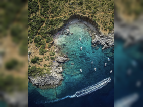 A stunning aerial view of a picturesque coastline with crystal-clear waters and several boats, showcasing the beauty of a tropical destination perfect for boating adventures.