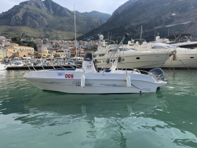 A sleek speedboat docked in a picturesque marina, surrounded by luxury yachts and scenic mountains, perfect for exploring coastal waters.