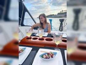 A beautifully set dining area on a boat featuring salads and glasses of white wine, perfect for a relaxing meal at sea.