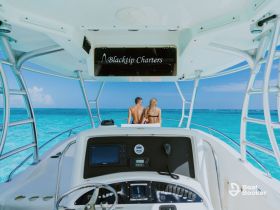 A couple enjoys a scenic view from the helm of a boat, capturing a romantic moment on the turquoise waters — perfect for unforgettable adventures with Blacktip Charters.