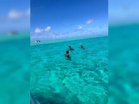 A group of individuals enjoys swimming in the crystal-clear turquoise waters, creating a perfect backdrop for a fun day on the water.