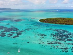 A stunning aerial view of turquoise waters surrounding a lush island, showcasing the beauty of coastal destinations perfect for boating adventures.