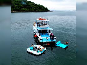 A lively group enjoys a fun day on the water, relaxing on a floating mat next to their boat — perfect for summer parties and aquatic adventures.