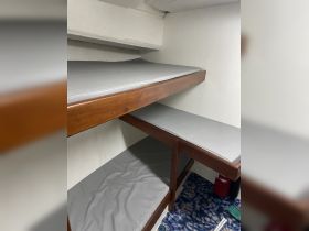 Interior view of a cozy cabin featuring bunk beds with gray cushions, ideal for comfortable sleeping arrangements on a boat.