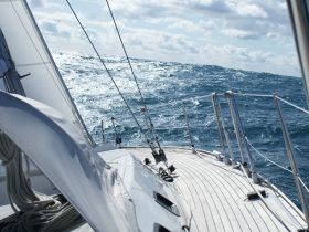 A stunning view from the deck of a sailboat navigating through sparkling waters, showcasing the beauty of sailing on open seas.