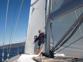 A sailor navigates a sailboat on open waters, showcasing the thrill of sailing and the beauty of the ocean.