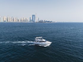 A stunning aerial view of a sleek yacht cruising through the waters with a backdrop of a modern skyline, perfect for showcasing luxury boating experiences.