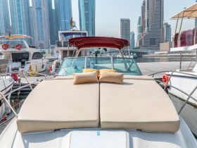 A cozy lounge area on a boat featuring plush cushions, perfect for relaxing while enjoying views of the marina and surrounding skyscrapers.