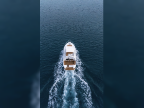 An aerial view of a sleek yacht cruising through calm waters, showcasing its elegant design and perfect for luxury boating experiences.