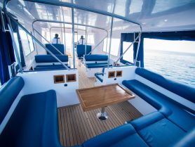 A spacious interior view of a boat's cabin featuring comfortable seating and a helm area, perfect for relaxing while cruising on the water.