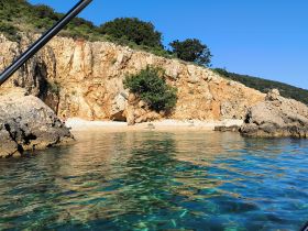 A picturesque view of a secluded beach with clear turquoise waters and rocky cliffs, featuring a person enjoying the serene environment — perfect for beach lovers and nature enthusiasts.
