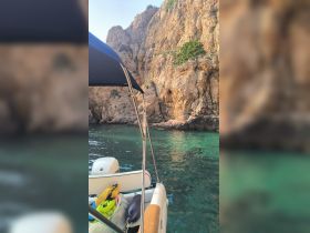 A serene view of a boat anchored near stunning rocky cliffs, showcasing the tranquil waters and natural beauty of the coastline.