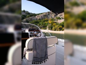 A cozy view of the helm and seating area inside a boat, showcasing a stylish blanket draped over the chair — perfect for relaxing on the water.