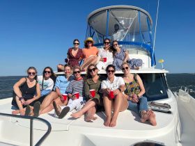 A lively group of friends enjoys a sunny day on a yacht, celebrating together with drinks and laughter — perfect for a memorable outing on the water.