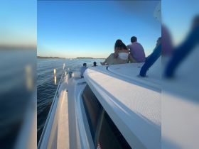 A group of friends enjoys a serene moment on the deck of a boat, taking in the beautiful sunset views — perfect for memorable outings on the water.