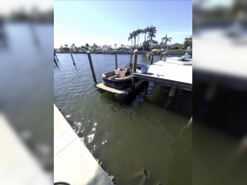 A pontoon boat is docked at a marina, surrounded by calm waters and palm trees, showcasing a serene boating environment.