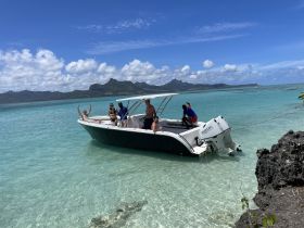 A lively group enjoys a sunny day on a boat in crystal-clear waters, perfect for beach outings and celebrations.