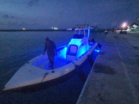A striking view of a boat illuminated with blue lights at dusk, showcasing its sleek design as it approaches the dock.