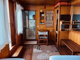A cozy interior view of a boat cabin featuring wooden finishes, seating, and amenities, perfect for relaxing during a nautical adventure.