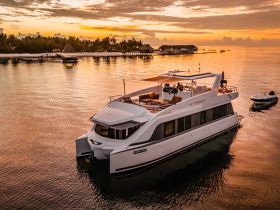A stunning aerial view of a luxurious yacht docked at sunset, surrounded by tranquil waters and lush palm trees, perfect for serene getaways.