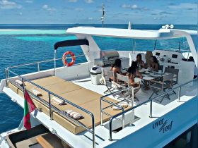 A group of friends enjoys a delightful meal on the deck of a luxury yacht, surrounded by stunning turquoise waters — perfect for a memorable day on the sea.