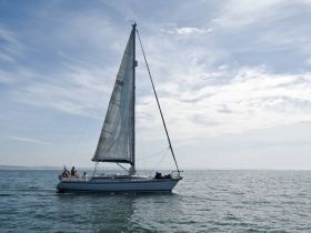 A sailboat glides gracefully across the water with guests onboard, enjoying a perfect day at sea.