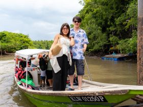 A cheerful group poses on a boat, ready for an adventure through lush mangroves — a perfect setting for exploring nature and enjoying the outdoors.