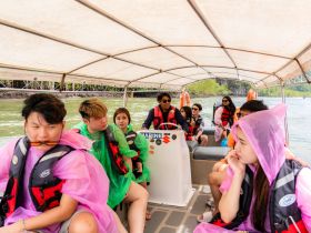 A lively group of friends enjoys a boat tour, dressed in colorful ponchos, as they navigate through scenic waters — perfect for adventure seekers.
