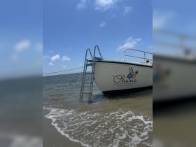 A close-up view of the 'Ohana private charter boat, partially docked in shallow waters under a clear blue sky, perfect for exploring coastal adventures.