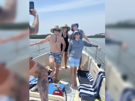 A cheerful group poses on the deck of a boat, enjoying a sunny day on the water — perfect for memorable outings and celebrations.