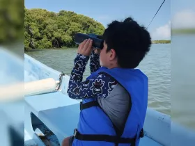 A child explores the surroundings from a boat using binoculars, embodying the spirit of adventure and discovery on the water.