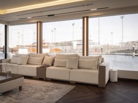 A stylish lounge area inside a luxury yacht, featuring comfortable seating and large windows offering views of the marina — perfect for relaxation and enjoying the scenery.