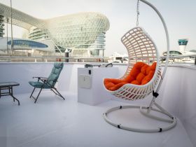 A cozy lounge area on a boat featuring a stylish hanging chair and a folding chair, perfect for relaxing while enjoying views of the marina.