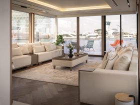 A beautifully designed interior lounge area of a luxury yacht, featuring comfortable seating and large windows that offer stunning views of the marina.