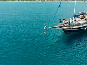 A lively scene captures guests jumping off a boat into the vibrant turquoise waters, showcasing the fun and excitement of a day on the water.