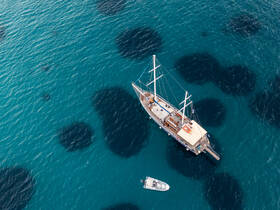 Aerial view of a majestic yacht sailing through crystal-clear waters, showcasing the beauty of the vessel against a stunning aquatic backdrop.