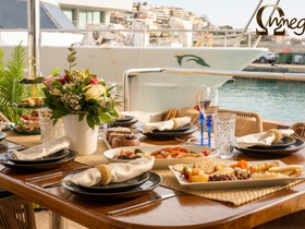 An elegantly set dining table on a yacht featuring a variety of gourmet dishes and drinks, perfect for onboard catering and special occasions.