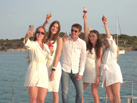 A group of friends celebrates aboard a yacht, raising their cocktails for a selfie against a scenic backdrop — perfect for memorable moments on the water.