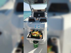 A beautifully arranged fruit platter and drinks are set up on the helm of a boat, perfect for enjoying refreshments while cruising on the water.