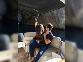 A couple shares an intimate moment aboard a boat, surrounded by stunning natural scenery — perfect for romantic getaways and special occasions on the water.