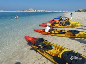 A vibrant scene of kayaks lined up on the beach, with a swimmer enjoying the clear waters — perfect for a day of adventure and water sports.