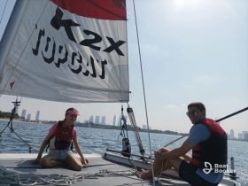 A young couple enjoys a sailing adventure on a Topcat catamaran, surrounded by stunning city views — perfect for water sports enthusiasts.