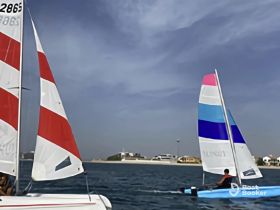Two colorful sailboats glide across the water, showcasing the thrill of sailing in a picturesque setting — perfect for water sports enthusiasts.