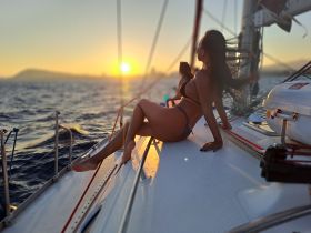 A woman enjoys a serene sunset aboard a sailboat, capturing the essence of relaxation and romance on the water.