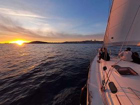 A serene sunset sailing experience with guests enjoying the view from the deck — perfect for romantic evenings on the water.