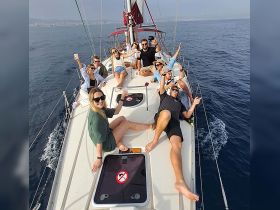 A lively group enjoys a sailing adventure, raising drinks and celebrating on the deck of a yacht — perfect for memorable outings with friends.